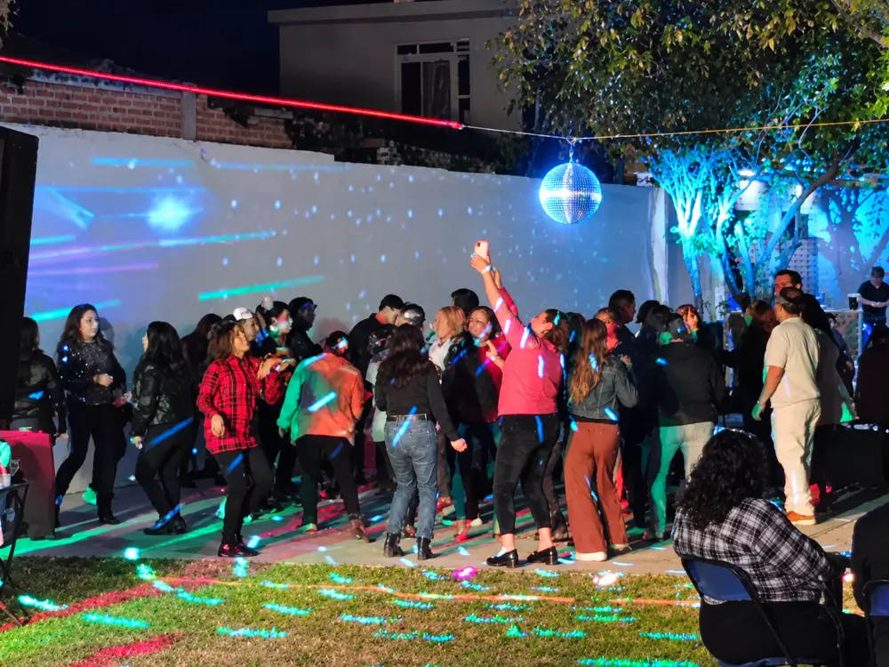 Invitados bailando en fiesta nocturna con esfera de espejos
