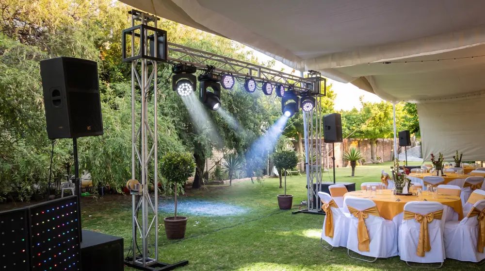 Jardín montado para evento con luces y bocinas sobre truss